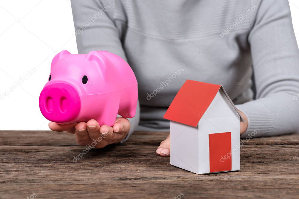 Woman holding piggy bank  and model home