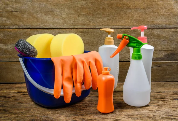 Caja llena de artículos de limpieza y guantes sobre fondo de madera — Foto de Stock