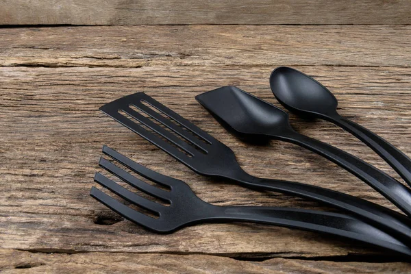 Black plastic kitchen set skimmer, spade of frying pan on wooden — Stock Photo, Image