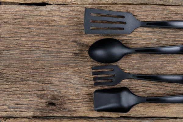 Black plastic kitchen set skimmer, spade of frying pan on wooden — Stock Photo, Image