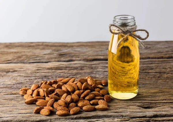 Peeled almonds with bowl and Bottle of almond oil on rustic wood — Stock Photo, Image