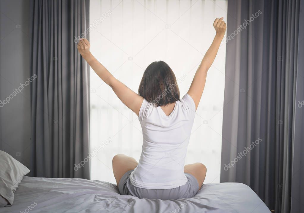 Asian Woman stretching in bed after wake up