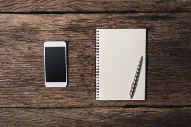 Kalem, not defteri, smartphone ile ofis ahşap büro. Üstten Görünüm 