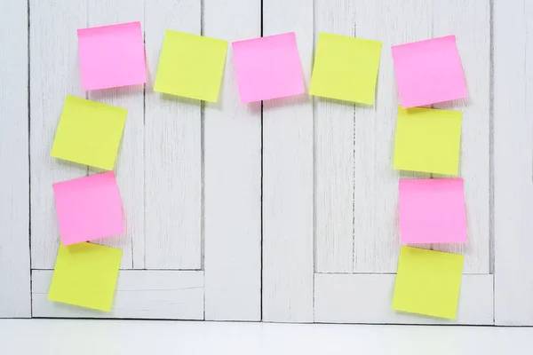 Many colorful sticky note, post note or post-it on white wooden
