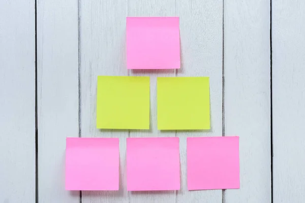 Many colorful sticky note, post note or post-it on white wooden