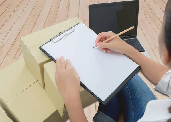 Mensajero toma notas en recibo de entrega entre paquetes en cajas — Foto de Stock