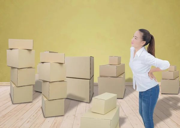 Женщина страдает от боли в спине при перемещении коробок — стоковое фото
