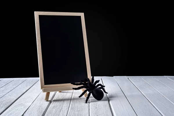 Die Kreidetafel auf dem Ständer mit der schwarzen Spinne auf Holz — Stockfoto