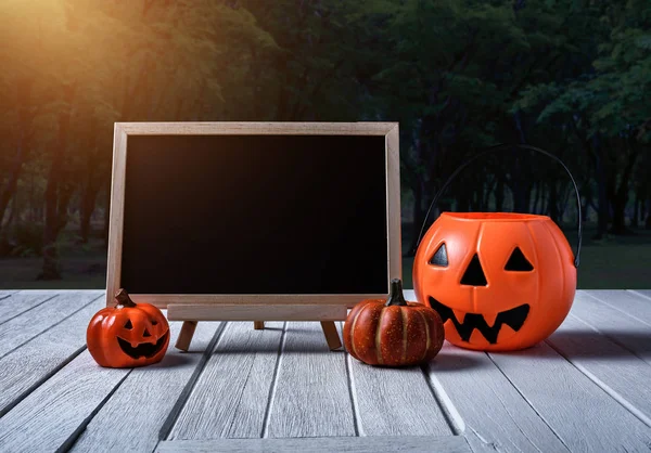 Halloween background. Spooky pumpkin, chalkboard on wooden floor