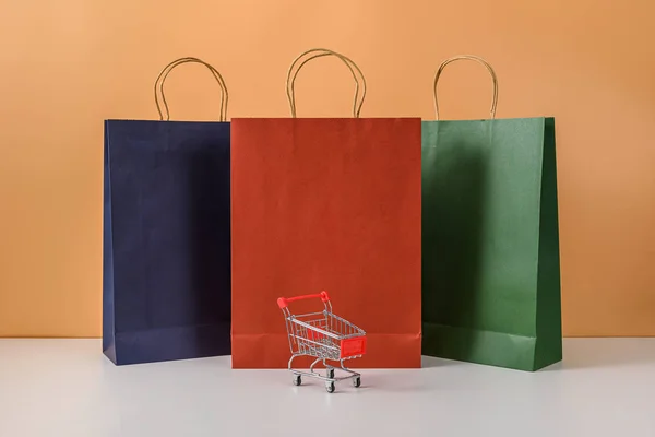Papírové nákupní tašky a nákupní košík nebo vozík s chytrým telefonem — Stock fotografie