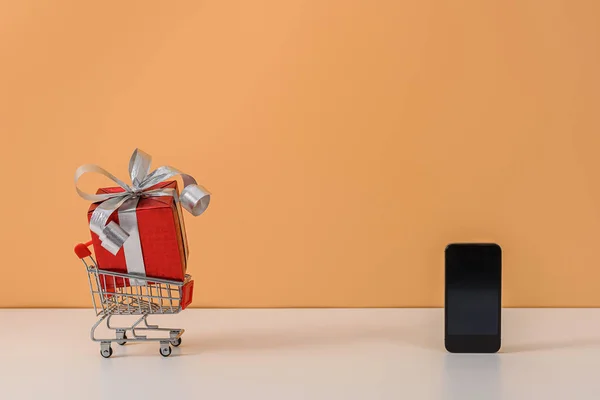 Kırmızı kurdeleli ve alışveriş arabalı bir sürü hediye kutusu.