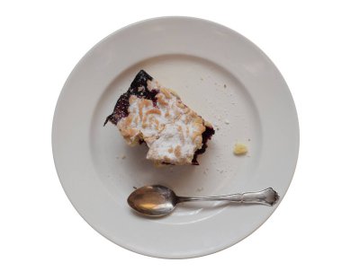 Reçelli bir dilim rendelenmiş kek ve beyaz arka planda izole edilmiş beyaz bir tabakta gümüş bir kaşık. Üst görünüm. 