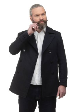 Beyaz gömlekli ve ceketli sakallı hippi beyaz arka planda bıyıklarını düzeltiyor.