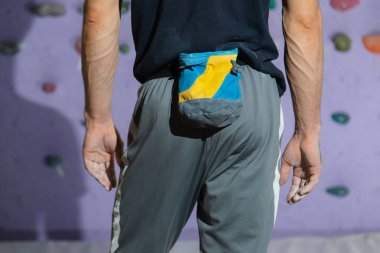 Güçlü ve kaslı bir sporcu yapay bir duvara tırmanmaya hazırlanıyor.