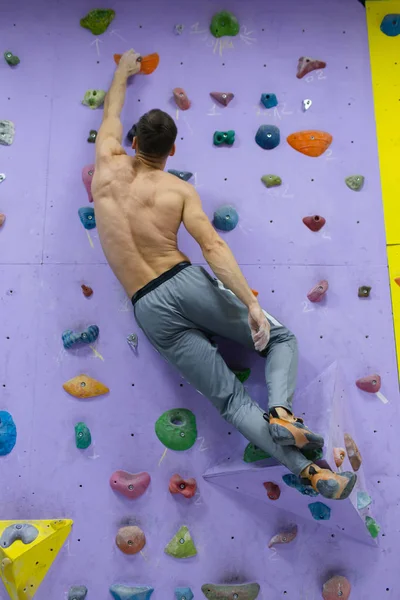 Muskularny mężczyzna ćwiczący wspinaczkę na skale w pomieszczeniach — Zdjęcie stockowe