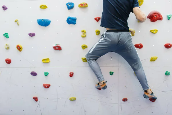 Silny i muskularny wspinaczka sportowa ćwiczenia na siłowni na sztucznej ścianie malowane w kolorze białym — Zdjęcie stockowe