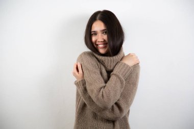 Bir şeye gülen neşeli bir modelin portresi. Bej kazaklı güzel bir bayan. Esmer kızın keyfi yerinde. Mutluluk ve güzellik kavramı. Beyaz arkaplanda izole