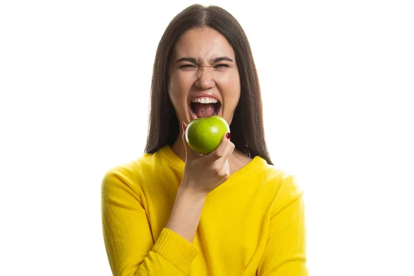 Mladá žena se zubatým úsměvem držící zelené jablko. izolovaný studiový portrét. — Stock fotografie