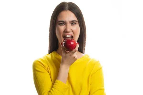 Mladá žena se zubatým úsměvem držící červené jablko. izolovaný studiový portrét. — Stock fotografie