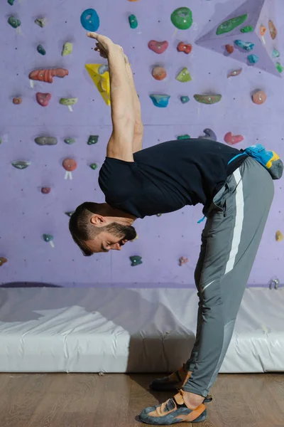 Alpinista esportivo forte e muscular se preparando para escalar uma parede artificial — Fotografia de Stock