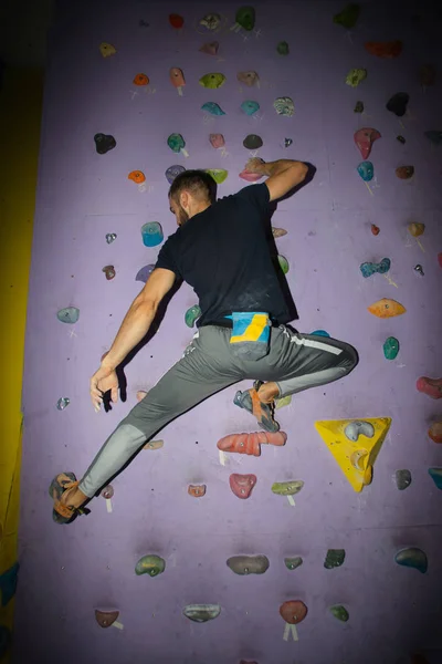 Escalador deportivo fuerte y musculoso haciendo ejercicio en el gimnasio en la pared artificial —  Fotos de Stock