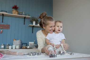 Annesiyle küçük bebek mutfak masasında un içinde oturuyor.