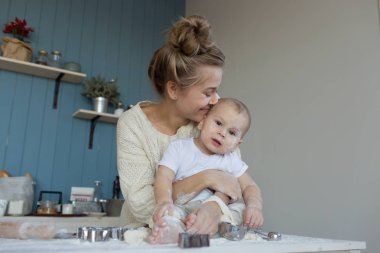 Annesiyle küçük bebek mutfak masasında un içinde oturuyor.