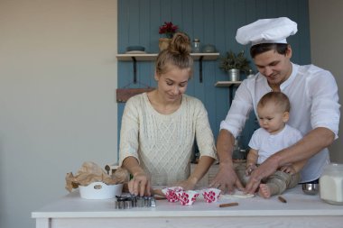 Annesi ve babasıyla birlikte mutfakta hamur, un, fırın ve ekmek ürünleri satan bir çocuk. Master sınıfı. Yemek yap ve öğren. 
