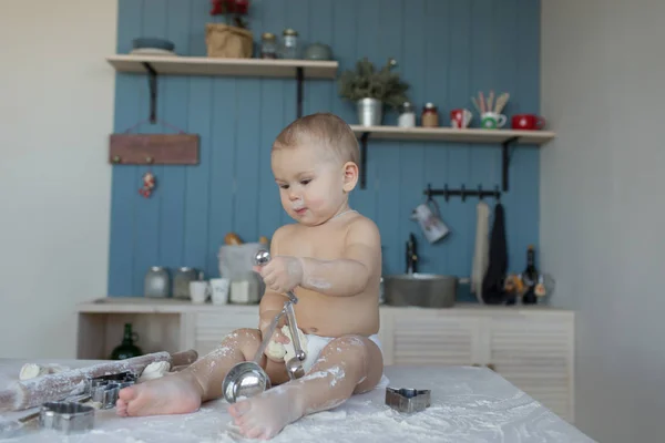 Little baby sitting on the kitchen table in flour — Stock Photo, Image