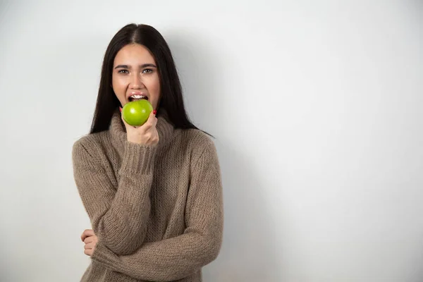 Молодая женщина с зубастой улыбкой держит зеленое яблоко. изолированный студийный портрет. — стоковое фото