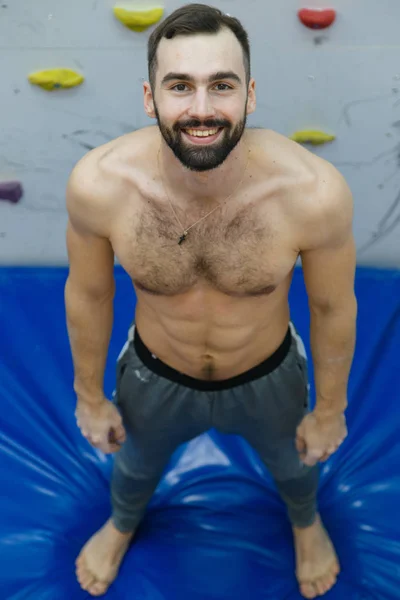 Portrait d'un grimpeur sportif fort et musclé faisant de l'exercice dans la salle de gym sur un mur artificiel — Photo