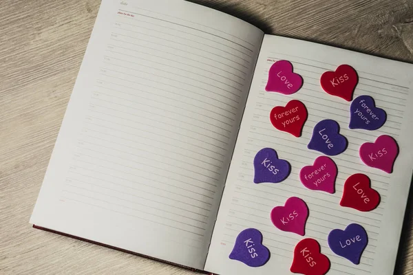 Sevgililer günü. Metin eklemek için not defteri. Küçük kalpler ahşap bir masa arka plan üzerinde. Boşaltmak.
