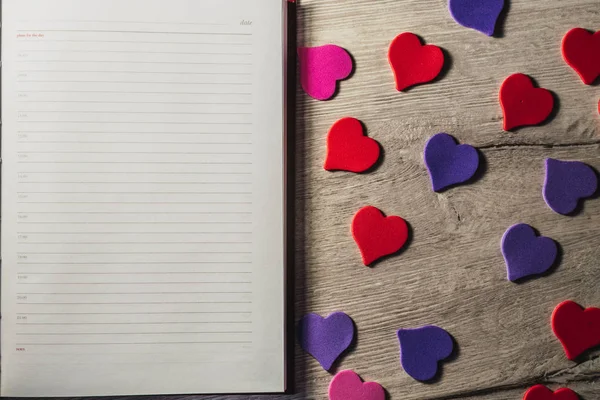 Sevgililer günü. Metin eklemek için not defteri. Küçük kalpler ahşap bir masa arka plan üzerinde. Boşaltmak.