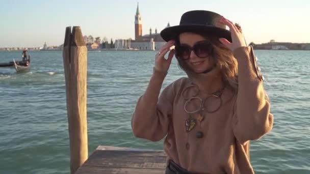Stylische Mädchen machen ihren Hut mit Gondoliere und Architektur im Hintergrund — Stockvideo