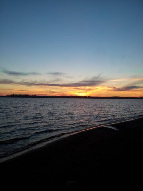 Baltık Denizi'nde sahilde bulutlar ile parlak turuncu gün batımı.