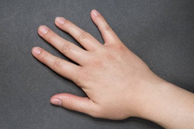 Gri yüzeyde doğal manikürlü genç beyaz kadın.