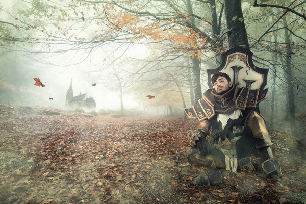 Young man cosplaying with fantasy knight costume resting in a dark forest