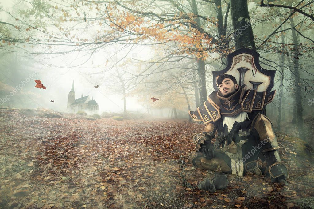 Young man cosplaying with fantasy knight costume resting in a dark forest