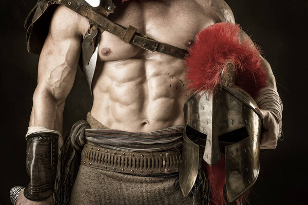 Древний воин или Гладиатор позирует на тёмном фоне

