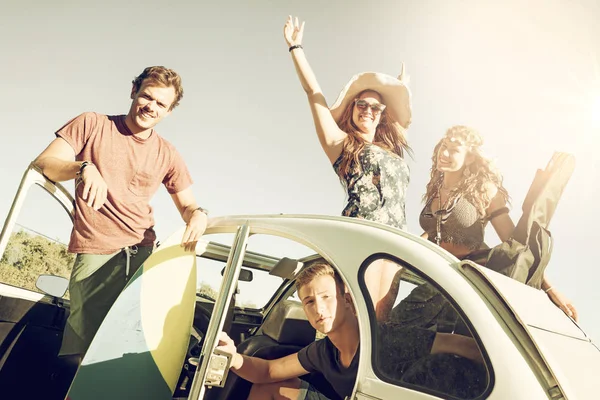 Group of happy people in a car in summertime ready for a roadtrip.