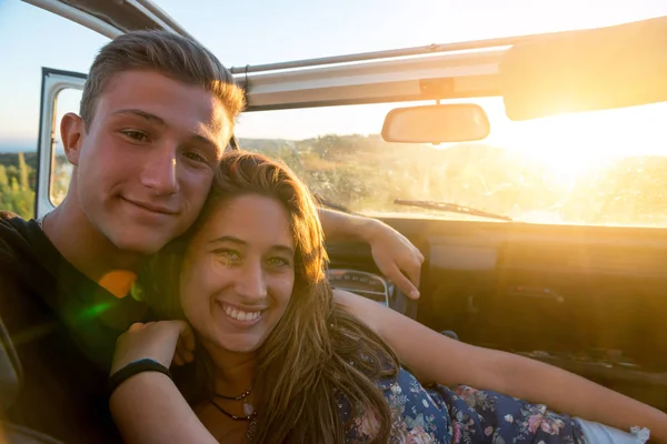 Happy couple in a car enjoying sunset.