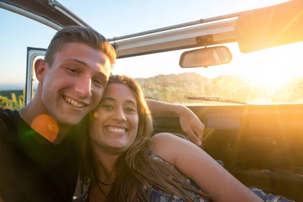 Happy couple in a car enjoying sunset.