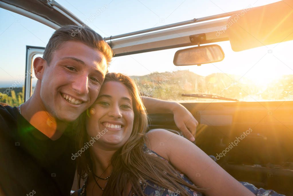 Happy couple in a car enjoying sunset.