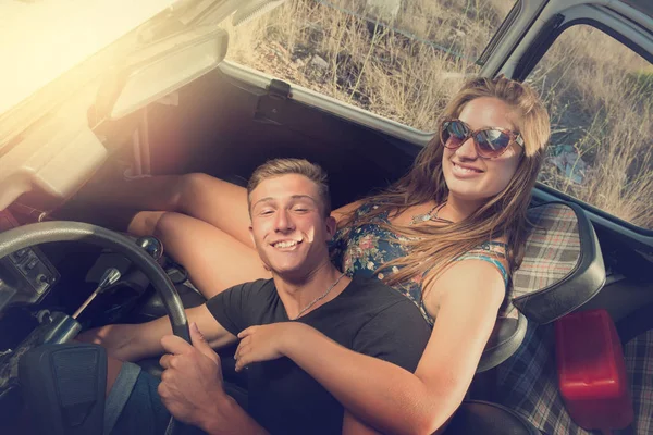 Couple in a car at sunset — Stock Photo, Image