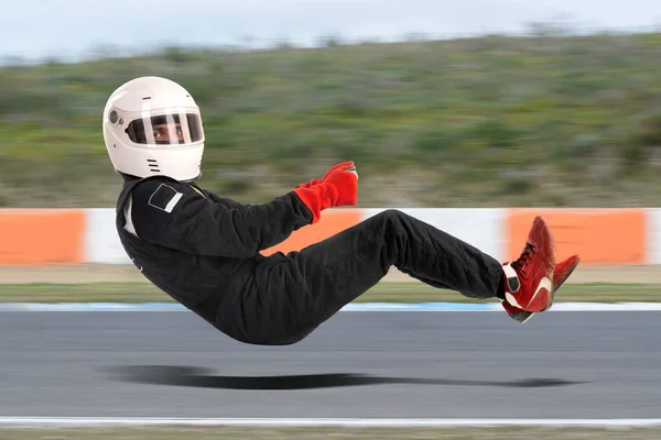 Racing driver in racing position with complete gear isolated in white