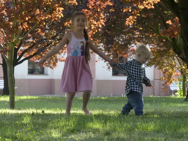 Prag, Çek Cumhuriyeti - 7 Mayıs 2018: Bahçede bir ağaç yakınındaki iki yaşında bir çocuk duruyor. Yakınındaki bir ağaç bahçe çim üzerinde sarışın bir çocuk duruyor.