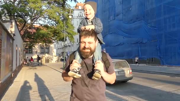 捷克布拉格 2018年5月7日 一名儿童坐在父亲的脖子上 他们在傍晚的阳光下走在大街上 慢动作 — 图库视频影像