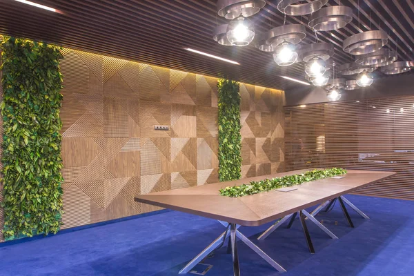 Interior of a modern office. Furniture in the office of the company. Large meeting table with live plants. Live plants in the wall of the negotiation room.