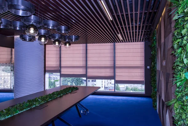 Interior of a modern office. Furniture in the office of the company. Large meeting table with live plants. Live plants in the wall of the negotiation room.