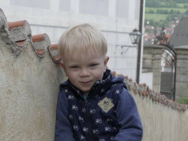 Cesky Krumlov, Çek Cumhuriyeti - 9 Mayıs 2018: eski şehrin arka planı poz iki yaşında bir çocuk